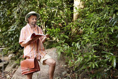 Fotografie, Obraz Middle aged European biologist or ecologist wearing hat and briefcase reading no