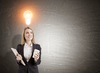 Wall Mural - Woman with coffee and notebook and a light bulb sketch on blackb