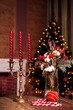 Christmas bouquet of red roses, flowers, cotton and green spruce branches, and the candlestick with red candles on the background of Christmas tree