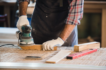 Worker grinds the wood of angular grinding machine