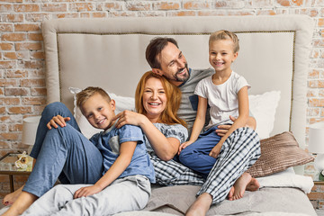 Happy family lying down on bed at home