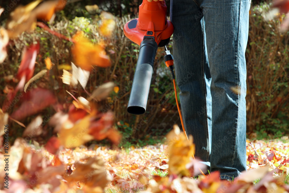Man working with  leaf blower: the leaves are being swirled up a - obrazy, fototapety, plakaty 