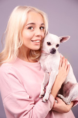 Wall Mural - Beautiful girl holding cute dog on grey background