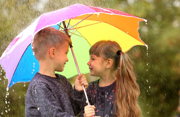 Portrait of cute children with umbrella in rain