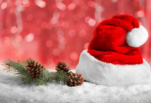 Santa Claus Hat With Christmas Decoration On Blurred Red Lights Background