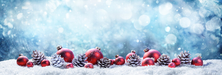 snowy christmas balls and pinecones in wintery scene