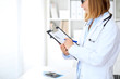 © rogerphoto - Close up of  female doctor  writing a medical prescription at clipboard while standing