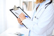 © rogerphoto - Close up of  female doctor  writing a medical prescription at clipboard while standing