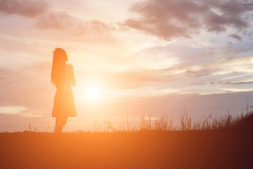 Wall Mural - Silhouette of woman praying over beautiful sky background