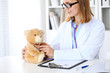 © rogerphoto - Female doctor examining a .Teddy bear  patient by stethoscope. Children medical care concept