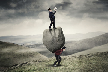 Canvas Print - Business people with boulder in the hill