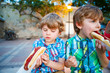 © Irina Schmidt - Two little kid boys eating hot dogs outdoors