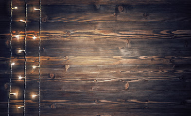 Christmas lights on rustic wooden background.