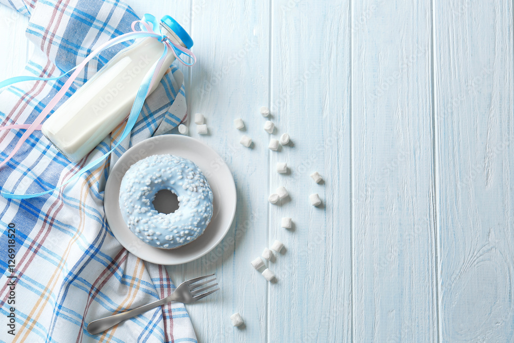 Plate with delicious donut and bottle of milk on table