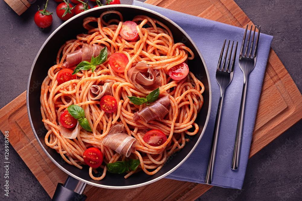 Spaghetti with amatriciana sauce and bacon in pan, top view