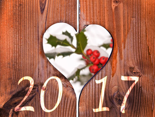 Wall Mural - 2017, wooden frame in the shape of a heart and branch of holly under the snow in the background