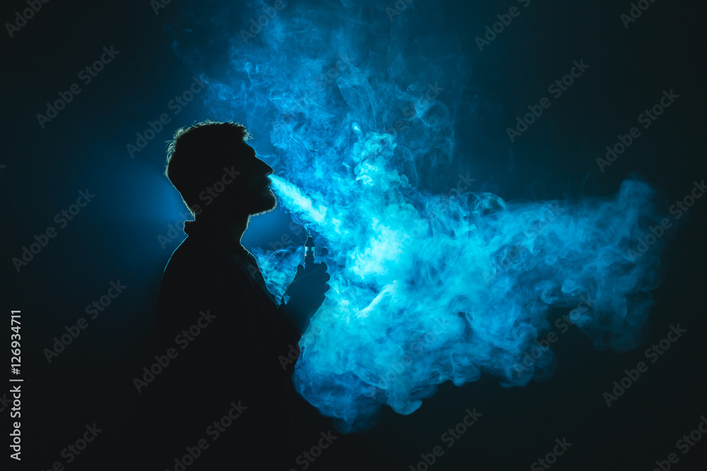 The man smoke a cigarette against the background of the blue light Stock  Photo