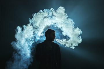 The man smoke a electronic cigarette on the dark background