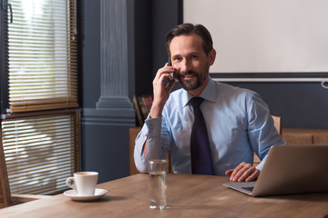 Handsome cheerful man speaking on the phone