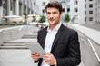Attractive young businessman using tablet near business center
