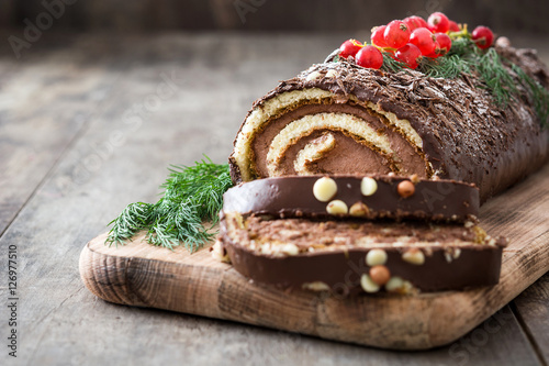 Photographie Chocolate yule log christmas cake with red currant on wooden background