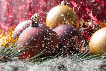 Christmas balls on fir branches covered with snow and Falling snowflakes