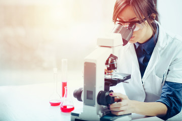 Young scientist looking through a microscope in a laboratory. Young scientist doing some research.