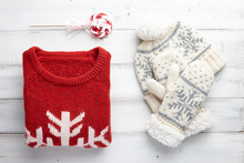 Winter Holiday Knitted Sweater, Mittens And Cap On White Wooden Background. Christmas Fashion Clothing Style.