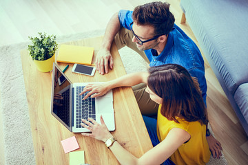 Wall Mural - Picture of young couple at home with laptop doing online shopping