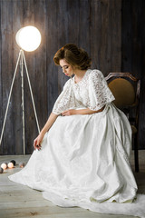 Wall Mural - portrait of a beautiful young girl with a stylish hair in white dress on a wooden background