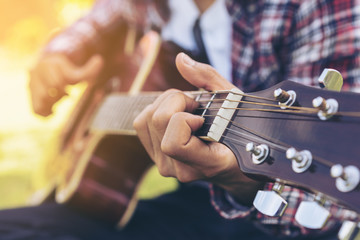 Man 's hand playing guitar, sitting on green grass