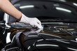 Car detailing series : Closeup of hand coating black car bonnet