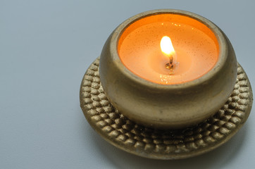 burning decorative candle in gold color on a light background
