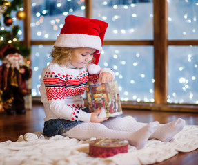 Little girl in red christmas hat with gift box