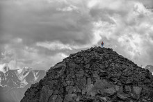 Silhouette Of A Girl With Backpack On Huge Mountain. Very Far. Epic Black-and-white Photo.