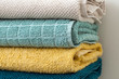 Stack of folded cotton bath towels in beige, turquoise, yellow and teal color, closeup