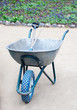 Garden wheelbarrow with blue wheel and gardening tools inside
