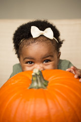 Wall Mural - cute baby girl with a pumpkin.