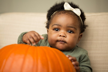 Wall Mural - cute baby girl with a pumpkin.