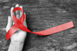 Red ribbon awareness on human hand with aged wood background with clipping path: World aids day: Symbolic concept for raising awareness campaign on people with HIV concept
