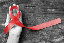 Red Ribbon Awareness On Human Hand With Aged Wood Background With Clipping Path: World Aids Day: Symbolic Concept For Raising Awareness Campaign On People With HIV Concept