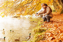 Senior Couple Feeding Ducks On The Lake