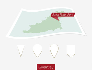 Curved paper map of Guernsey with capital Saint Peter Port on Gray Background.