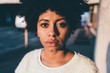 Portrait of young beautiful afro woman outdoor in the city looking at camera, serious - pensive, rebel concept