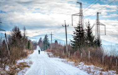 snowy road among mountains and high voltage lines