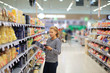 © lado2016 - Woman shopping in supermarket reading product information. Checking list.