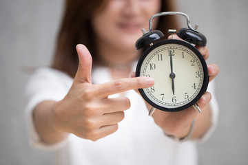 Wall Mural - Asian women hand and point finger to retro clock times at 6 o'clock, It's time to do something concept