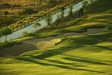 Sand bunker on the green golf course at sunrise