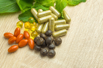 Herbal pills with healthy medical plant. Green leaf, alternative drug on wood ground