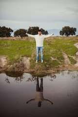 Canvas Print - Attractive guy with jeans and white jersey next to a river